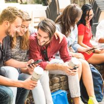 Multiracial millennials group using smart phone at city college backyard - Young people addicted by mobile smartphone - Technology concept with connected trendy friends - Warm vibrance sunshine filter