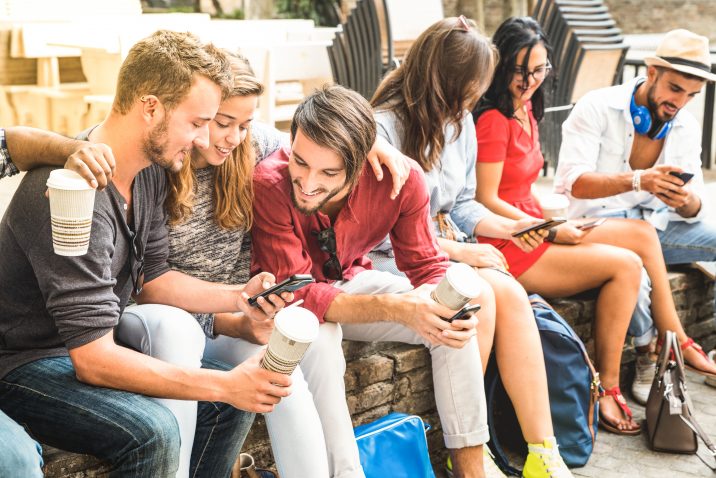 Multiracial millennials group using smart phone at city college backyard - Young people addicted by mobile smartphone - Technology concept with connected trendy friends - Warm vibrance sunshine filter