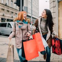 Happy two girls holding bunch of shopping bags