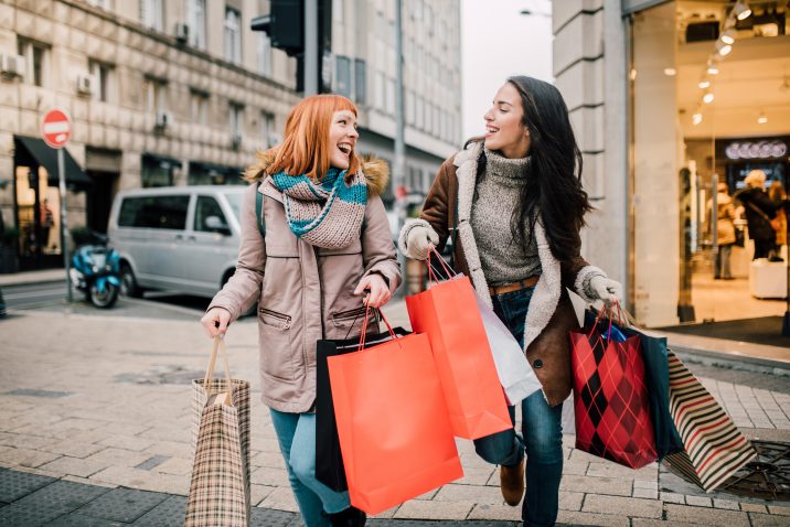 Happy two girls holding bunch of shopping bags