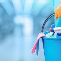 Concept of quality cleaning. The cleaning lady standing with a bucket and cleaning products.