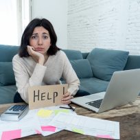 Portrait of worried young woman feeling stressed and desperate asking for help in paying bills, debts, tax expenses and accounting home finances with laptop. In online banking and financial problems.