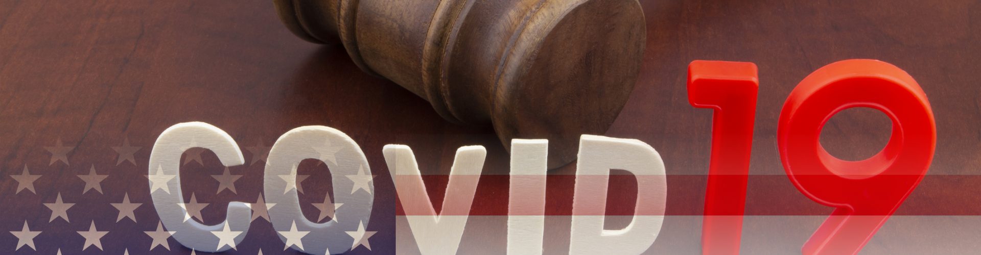 Wooden judge gavel with letters covid19 on table and usa flag. Concept of quarantine and law against covid-19.