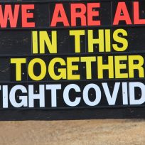 A sign or billboard in front of a business that states we are all in this together fight Covid-19.