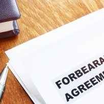 Forbearance agreement papers with pen and notepad.