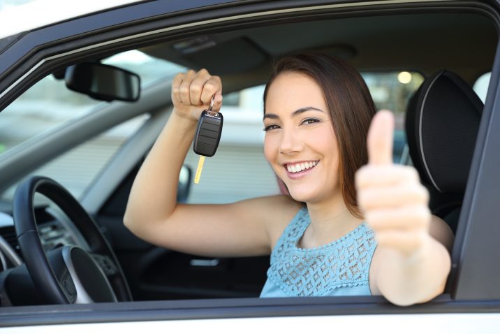 Happy car owner with a key and thumbs up