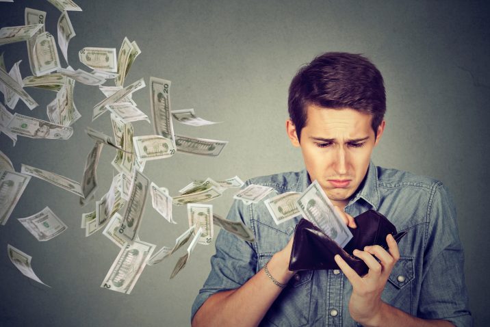 Man looking at wallet with money dollars flying away