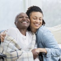 Woman embraces her wheelchair-bound mother