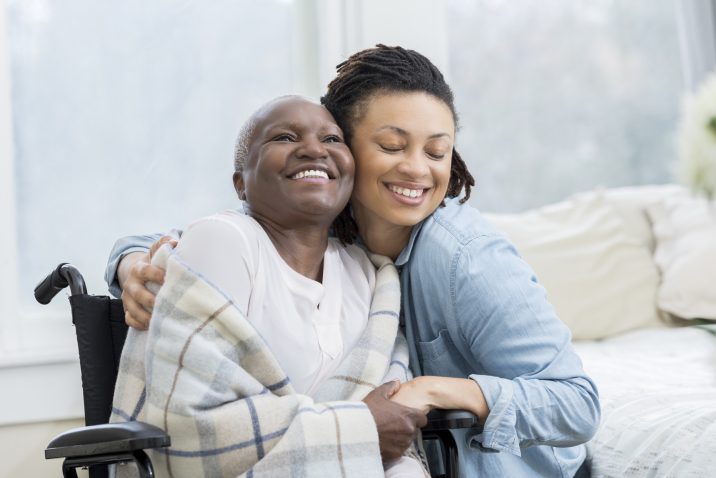 Woman embraces her wheelchair-bound mother